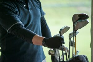 Golfer picking golf club from caddy on golf course