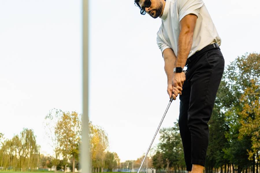 Close-up of golfer in glasses making putt on course