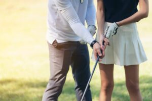 Golf teaching professional fixing player’s grip on golf club 