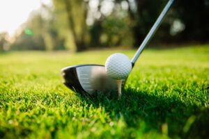 Golf club and golf ball on a green lawn